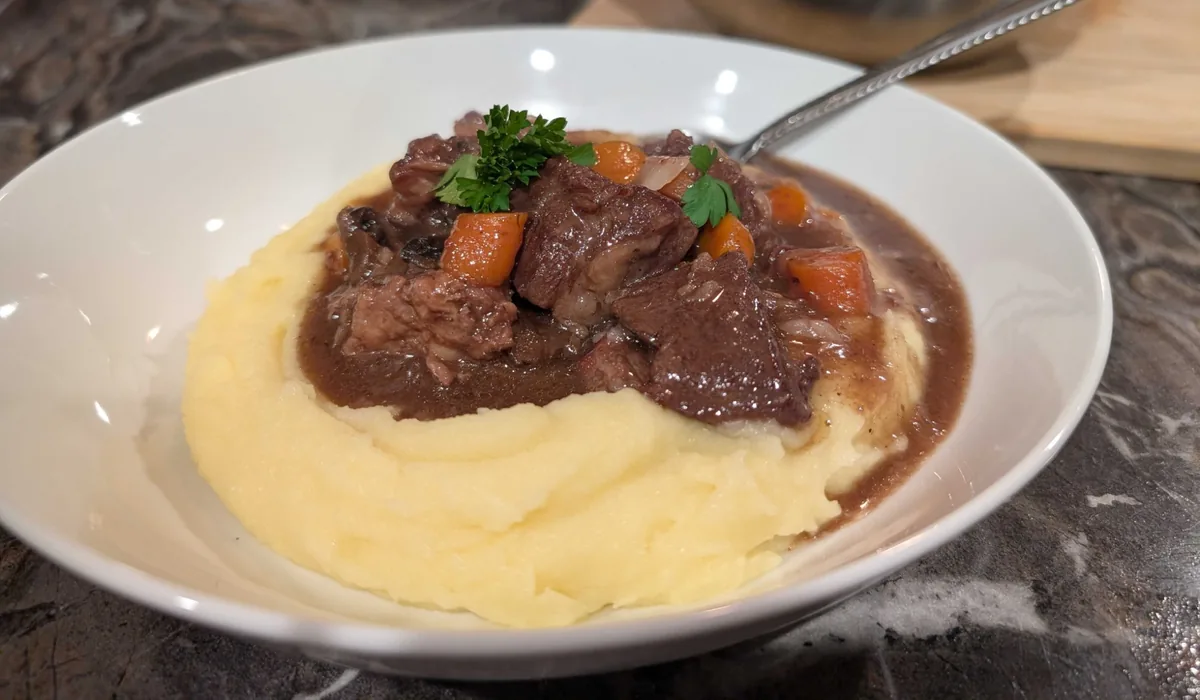 A low side view of the bourguignon bowl, the sauce pooling around a swirl of potato purée
