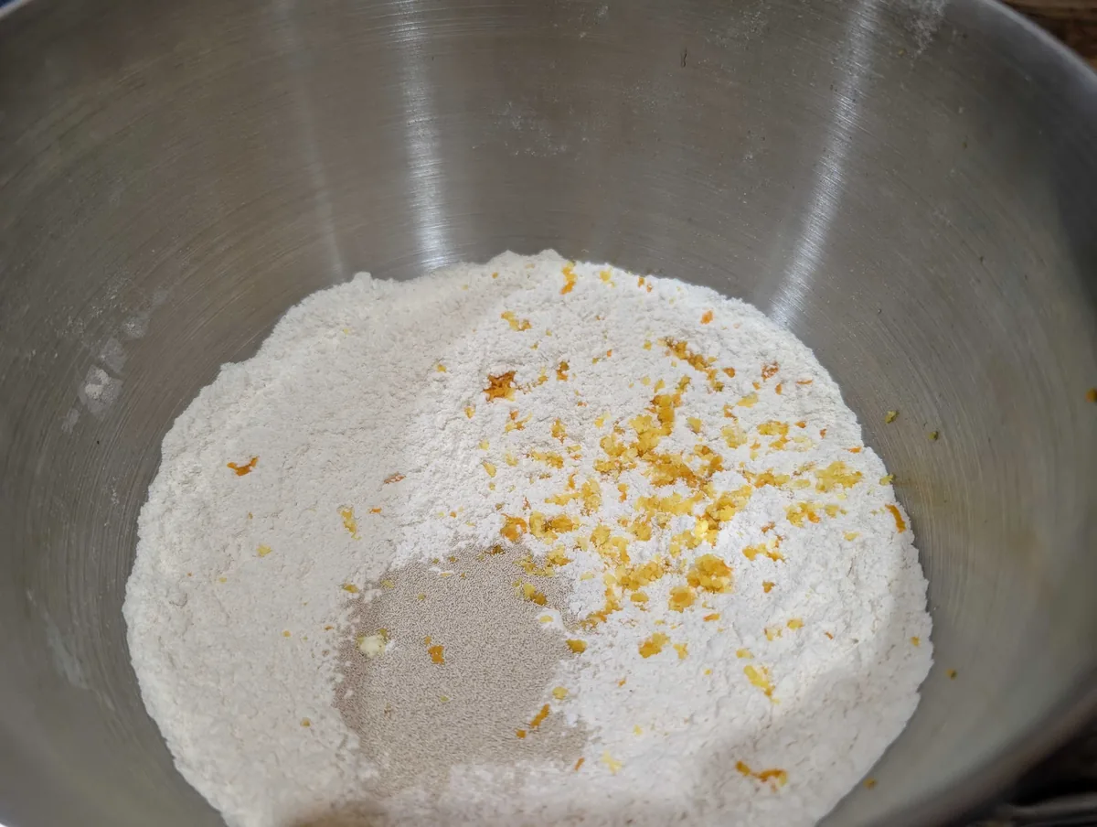 Bread flour and whole-wheat flour in a mixer bowl with instant yeast and grated orange zest on top