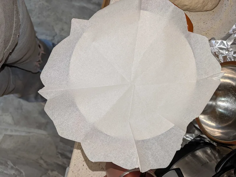 The parchment unfolded into a rough round, held over the Dutch oven