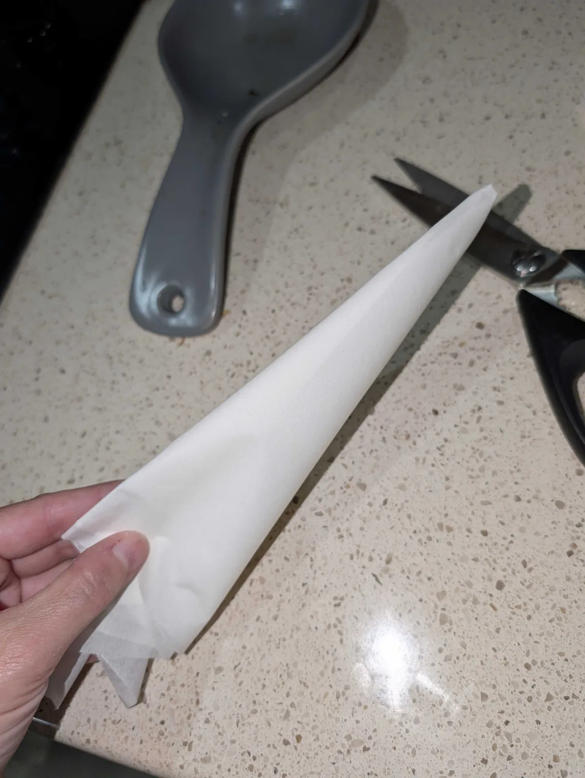 The parchment folded into a narrow wedge, held next to a pair of kitchen scissors
