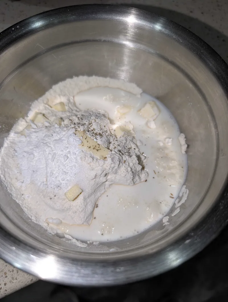 Flour, baking powder, cubes of cold butter, herbs and milk in a steel bowl, just before mixing the dumplings