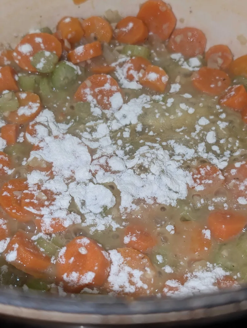 Flour sprinkled over the carrots and celery in the pot before the stock goes in