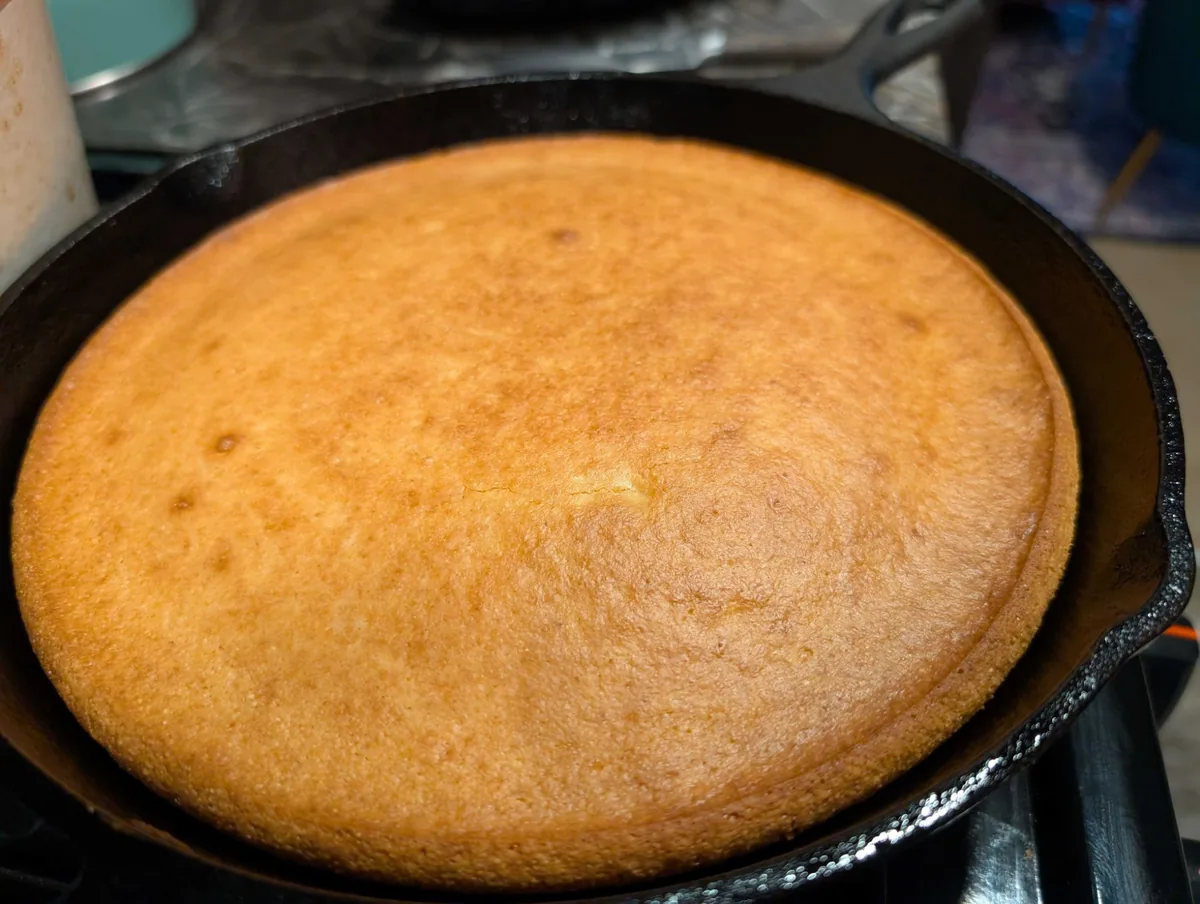 A golden round of honey cornbread, fresh from the oven in a cast iron skillet