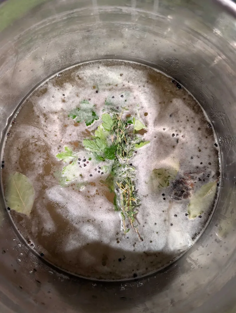 The chicken under the foamy Oberon brine, with thyme, parsley, bay leaves and peppercorns floating on top