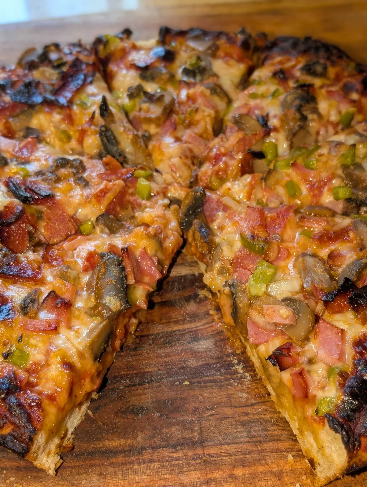 The pizza on a board with a wedge pulled away to show the deep layers