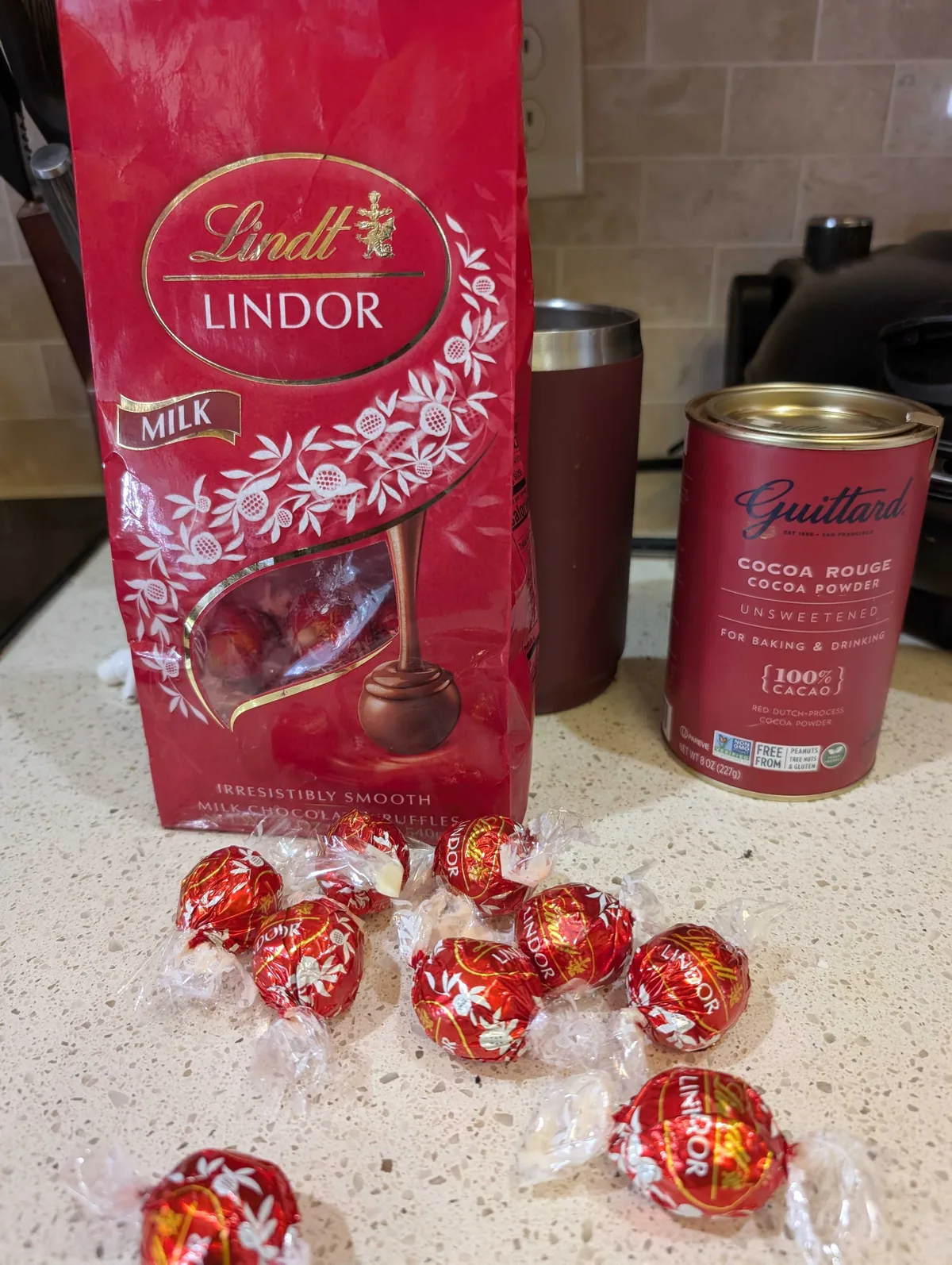 A red bag of Lindt Lindor milk chocolate truffles with unwrapped truffles scattered on the counter